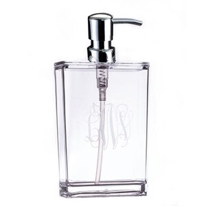 May include: A clear acrylic soap dispenser with a silver pump and a monogrammed design. The monogram is the letters "GMS" in a script font.