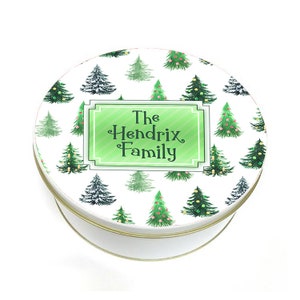 May include: White round tin with a green and white Christmas tree pattern. The text "The Hendrix Family" is printed in a green rectangle in the center of the tin.