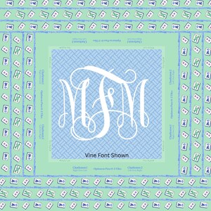May include: A square, light blue and green Mahjong game board with a white monogram in the center. The board features a light blue woven pattern and a border of Mahjong tiles.