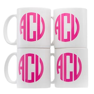 May include: Set of four white ceramic mugs with a pink monogram of the letters "ACV" on each mug.