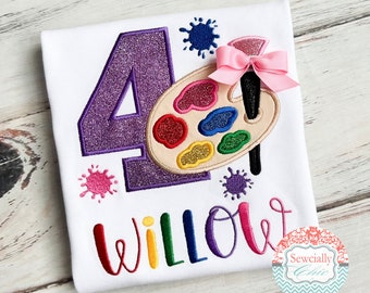 Könnte beinhalten: Weißes T-Shirt mit einer großen, lila glitzernden Zahl 4. Eine farbenfrohe Künstlerpalette und ein Pinsel befinden sich auf der rechten Seite. Der Name "Willow" ist in Regenbogenfarben gestickt. Rosa Schleife und Farbspritzer.