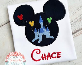 Puede incluir: Camiseta blanca con una silueta negra de la cabeza de Mickey Mouse. Dentro de la silueta hay un castillo azul y blanco con globos de colores. El nombre "CHACE" está bordado en rojo debajo de la silueta.