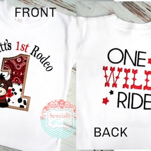 K&ouml;nnte beinhalten: Wei&szlig;es T-Shirt mit einem roten und schwarzen Stickmotiv auf der Vorderseite. Das Motiv zeigt eine Comic-Kuh und den Text "Wyatt's 1st Rodeo". Die R&uuml;ckseite des Shirts tr&auml;gt den Text "ONE WILD RIDE" in Rot und Schwarz.