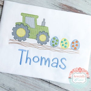 May include: Green tractor pulling a line of colorful Easter eggs with the name Thomas embroidered in blue below.