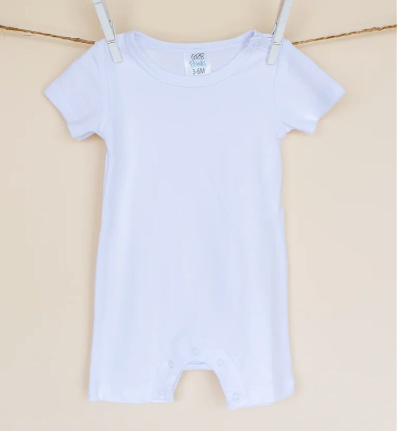 May include: White short-sleeve baby onesie with a tag that reads "100% Blanks 3-6M".