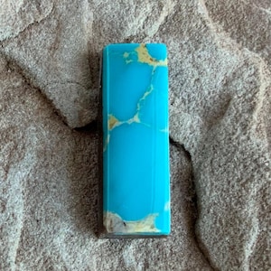 May include: A rectangular turquoise cabochon with a blue and white marbled pattern. The stone is set in a silver bezel.