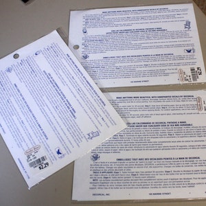 Puede incluir: Dos hojas de instrucciones blancas con texto azul para aplicar calcoman&iacute;as. Las instrucciones est&aacute;n en ingl&eacute;s, espa&ntilde;ol y franc&eacute;s. Las hojas est&aacute;n etiquetadas "Decorcal, Inc." y tienen una etiqueta de precio de 2,29&nbsp;&euro;.