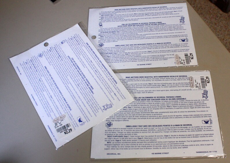 Puede incluir: Dos hojas de instrucciones blancas con texto azul para aplicar calcoman&iacute;as. Las instrucciones est&aacute;n en ingl&eacute;s, espa&ntilde;ol y franc&eacute;s. Las hojas est&aacute;n etiquetadas "Decorcal, Inc." y tienen una etiqueta de precio de 2,29&nbsp;&euro;.