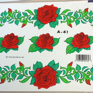 Puede incluir: Una hoja de calcoman&iacute;as de rosas rojas con hojas y enredaderas verdes. La hoja incluye cinco rosas y dos dise&ntilde;os de enredaderas. El texto "A-41" y "1980 DECORCAL INC" est&aacute;n impresos en la hoja.