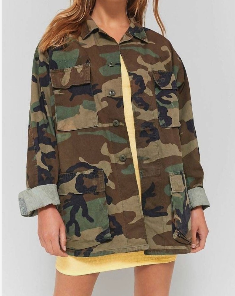 May include: A green, brown and black camouflage jacket with a button-up front and multiple pockets.