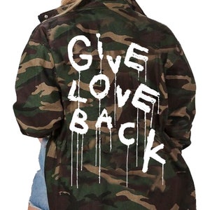 May include: A green and brown camouflage jacket with the words "GIVE LOVE BACK" written in white paint on the back.