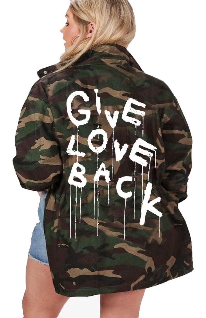 May include: A green and brown camouflage jacket with the words "GIVE LOVE BACK" written in white paint on the back.