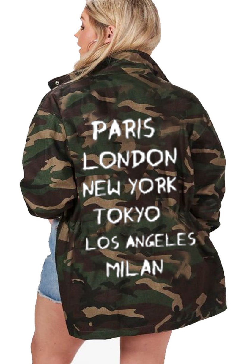 May include: A camouflage green jacket with white text on the back that reads "Paris, London, New York, Tokyo, Los Angeles, Milan".