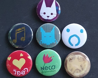 Puede incluir: Siete botones redondos con pasador con diferentes diseños. Los botones presentan una nota musical, un gato, una flor, una estrella, un corazón, una cara y un gato con rayas. Los botones son de diferentes colores y tienen un acabado brillante.