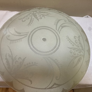 May include: A white frosted glass lampshade with a floral pattern. The lampshade has a small hole in the centre.