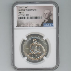 Puede incluir: Una moneda de medio dólar de plata de 1982-D con la imagen de George Washington, calificada como MS 66 por NGC. La moneda está en una placa de plástico transparente con una etiqueta blanca. La etiqueta incluye el año, la marca de la ceca, la denominación y la calificación. La moneda presenta un retrato de George Washington en el anverso y una representación de él a caballo en el reverso.
