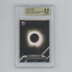 May include: A graded trading card featuring a photo of the 2024 solar eclipse. The card is from the Topps Now series and is labeled as the "1st Total Eclipse Graces North America Since 2017". The card is graded 9.5 GEM MINT.