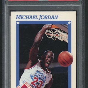 May include: A 1991 Hoops Michael Jordan All-Star trading card. The card features an action shot of Michael Jordan dunking a basketball. The card is encased in a protective holder. The card has the text "NBA All-Star Weekend Charlotte Feb 8-10 1991".