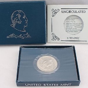 Puede incluir: Una caja azul con una moneda de plata en su interior. La moneda está en una caja de plástico transparente. La caja tiene las palabras "United States Mint" impresas en la parte delantera. La caja también tiene una pequeña tarjeta con las palabras "Sin circular 1792-1982" impresas en ella.