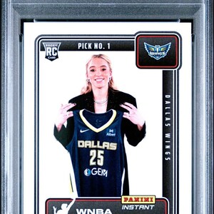 May include: A graded sports trading card featuring Paige Bueckers from the 2025 Panini Instant WNBA Draft Night. The card displays a photo of Bueckers holding a Dallas Wings jersey. The card is graded GEM MT 10 by PSA.