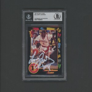 May include: A signed basketball card featuring Larry Johnson, a center for the Charlotte Hornets. The card is from the 1991-92 Wild Card series and is graded by Beckett Authentication Services. The card is in a protective case.