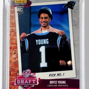 May include: A Panini Instant RC card featuring Bryce Young of the Carolina Panthers. The card shows Young holding his jersey with the number 1. The card is encased in a protective holder, with the NFL Draft 2023 logo visible.