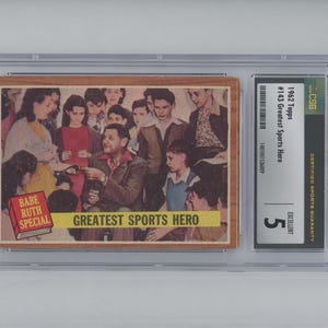 Puede incluir: Una tarjeta de béisbol Topps de 1962 con Babe Ruth, etiquetada como "Greatest Sports Hero." La tarjeta está en excelente estado y tiene una calificación de 5 por CSG.
