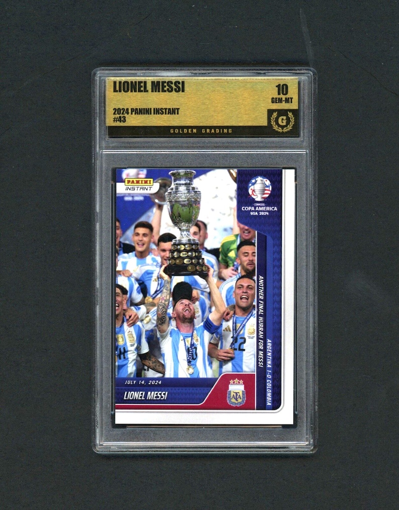 May include: A graded Panini Instant card featuring Lionel Messi. The card shows Messi holding a trophy with his team, celebrating a victory. The card is graded 10 GEM-MT by Golden Grading, with the text "COPA AMERICA USA 2021" and "ARGENTINA 1-0 COLOMBIA".