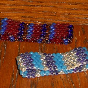 May include: Two beaded bracelets, one with red, blue, and gold beads, and the other with blue, white, and purple beads.