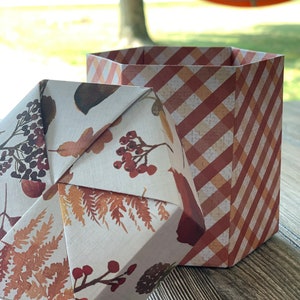 May include: A hexagonal origami box with a white background and a floral pattern in shades of brown and red. The box is open and the inside is lined with a red and white gingham pattern.