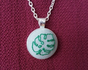 Embroidered necklace pendant with a monstera leaf