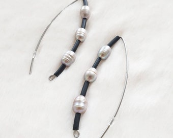 May include: A pair of silver earrings with black string and pearl accents. Each earring has three pearls.