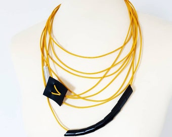 Collana bavaglino in pelle gialla: gioielli contemporanei asimmetrici