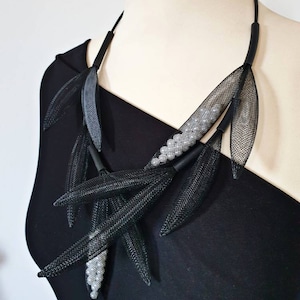 May include: A black mesh necklace with silver beads and leaf-shaped accents.