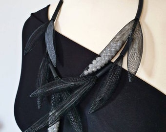 May include: A black mesh necklace with silver beads and leaf-shaped accents.