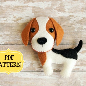 May include: A handcrafted felt dog toy in white, brown, and black. The dog features large floppy ears, a black nose, and button eyes. The text "PDF PATTERN" is displayed in a yellow label.