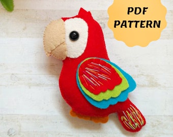 May include: PDF pattern for a felt parrot toy. The parrot is red with blue and green wings and a beige beak. It has a black eye and colorful embroidery on its wings and tail.