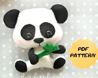 May include: A white and black felt panda bear holding a green bamboo shoot. The panda has black eyes and a pink nose. The text "PDF PATTERN" is on a yellow circle in the background.