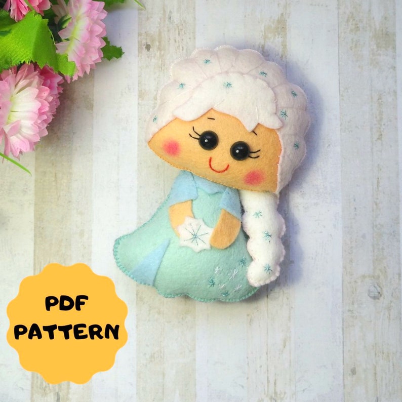May include: A felt doll pattern for a character with a white and blue dress, white hair, and a snowflake in her hand. The pattern is labeled "PDF PATTERN".