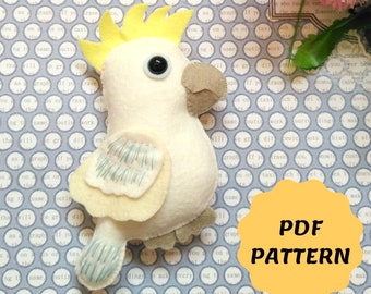 May include: A PDF pattern for sewing a white cockatoo plush toy. The cockatoo has a yellow crest, black eyes, and blue wings. The pattern is available for download.