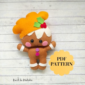May include: A gingerbread person felt toy pattern in PDF format. The gingerbread person is brown with white icing, pink cheeks, and black eyes. The toy has a green holly leaf and red berry on top of its head. The pattern is available for download.
