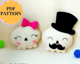 May include: A PDF pattern for two felt skull ornaments. One skull is wearing a black top hat and a black mustache. The other skull is wearing a pink bow. The pattern is titled "PDF PATTERN".