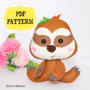 May include: A brown felt sloth plush toy with a white face, brown eyes, and a small green leaf on its head. The toy is sitting on a white surface. The text "PDF PATTERN" is in a yellow banner above the toy.