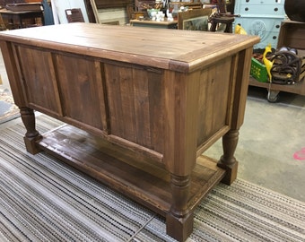 May include: A rustic wooden console table with a dark brown finish. The table has a single shelf and turned legs.