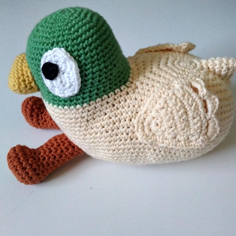 Peut inclure: Un jouet en peluche de canard crochet&eacute; avec une t&ecirc;te verte, un corps cr&egrave;me et des pieds orange.
