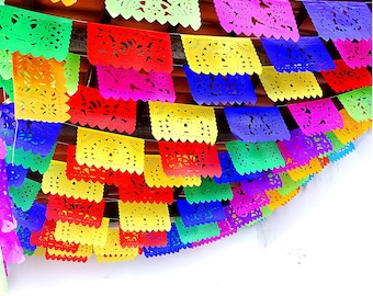 May include: A colorful string of paper decorations, known as papel picado, hangs from a ceiling. The decorations are cut in a variety of intricate patterns and feature a rainbow of colors, including red, orange, yellow, green, blue, purple, and pink.