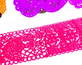 May include: Close-up of colorful paper cutouts in shades of pink, purple, and brown. The pink cutout features a floral design with a scalloped edge. The purple and brown cutouts have a circular design. The cutouts are on a white background.