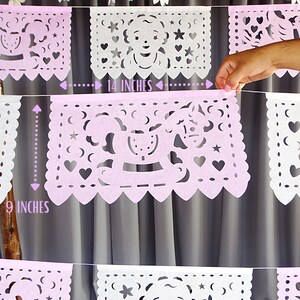 May include: A pink and white paper banner with cut-out designs. The banner is 14 inches wide and 9 inches tall. The designs include stars, hearts, and a rocking horse.