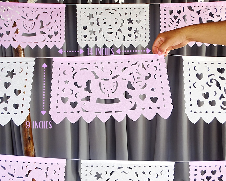 May include: A pink and white paper banner with cut-out designs. The banner is 14 inches wide and 9 inches tall. The designs include stars, hearts, and a rocking horse.