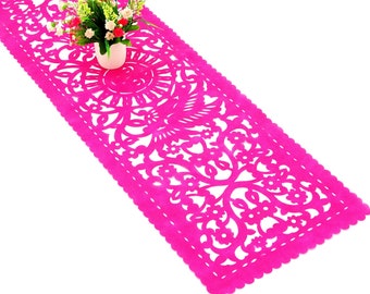 May include: A pink table runner with a delicate floral and bird design. The runner is made of paper and has a scalloped edge.
